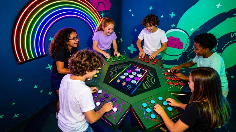 Six enfants autour d&rsquo;une table à boutons lumineux dans une salle de Cube Challenges