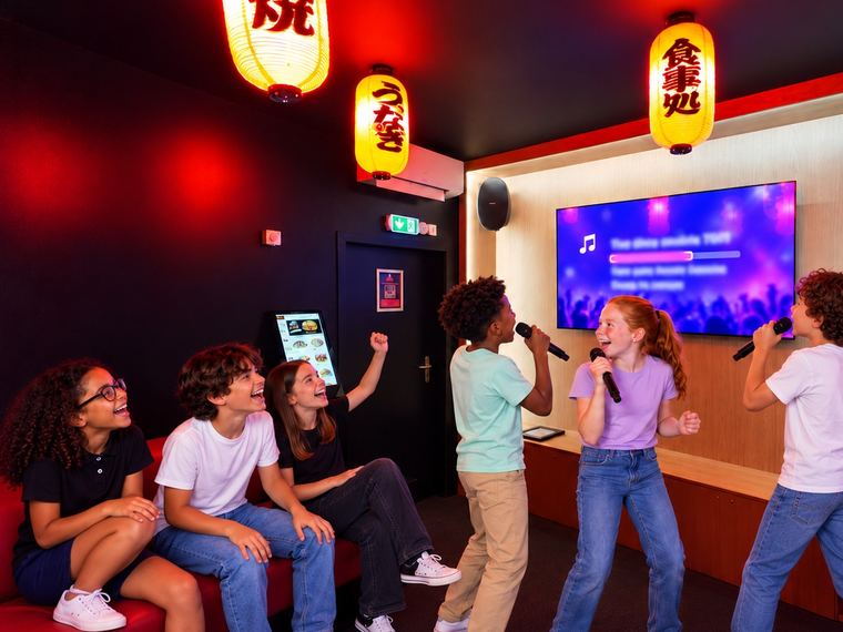 Des enfants chantent face à l&rsquo;écran où défilent les paroles