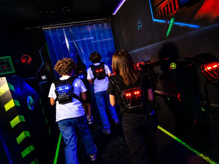 Des enfants équipés de leur gilet entrent dans le labyrinthe du laser game