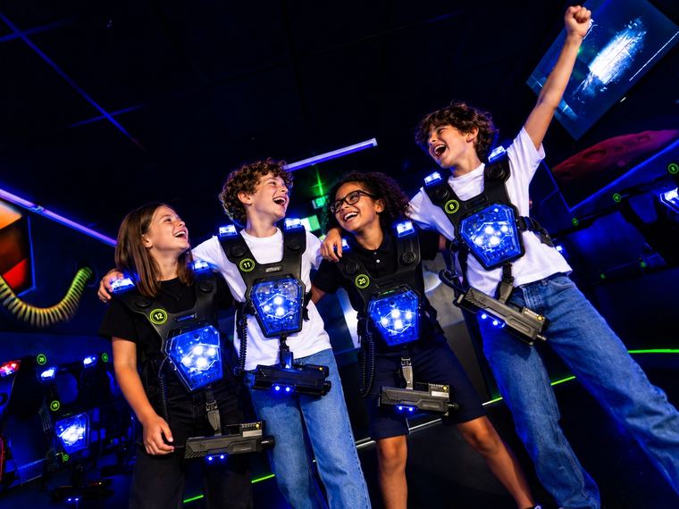 Quatre enfants en gilet bleu fêtent la fin de leur partie de laser game