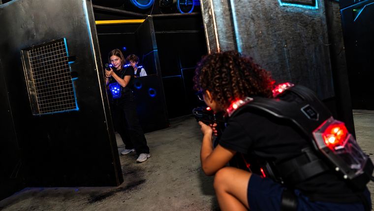 Deux équipes d&rsquo;enfants en gilet lumineux se font face dans le labyrinthe du laser game