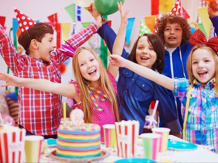 Enfants autour du gâteau d’anniversaire, bras levés