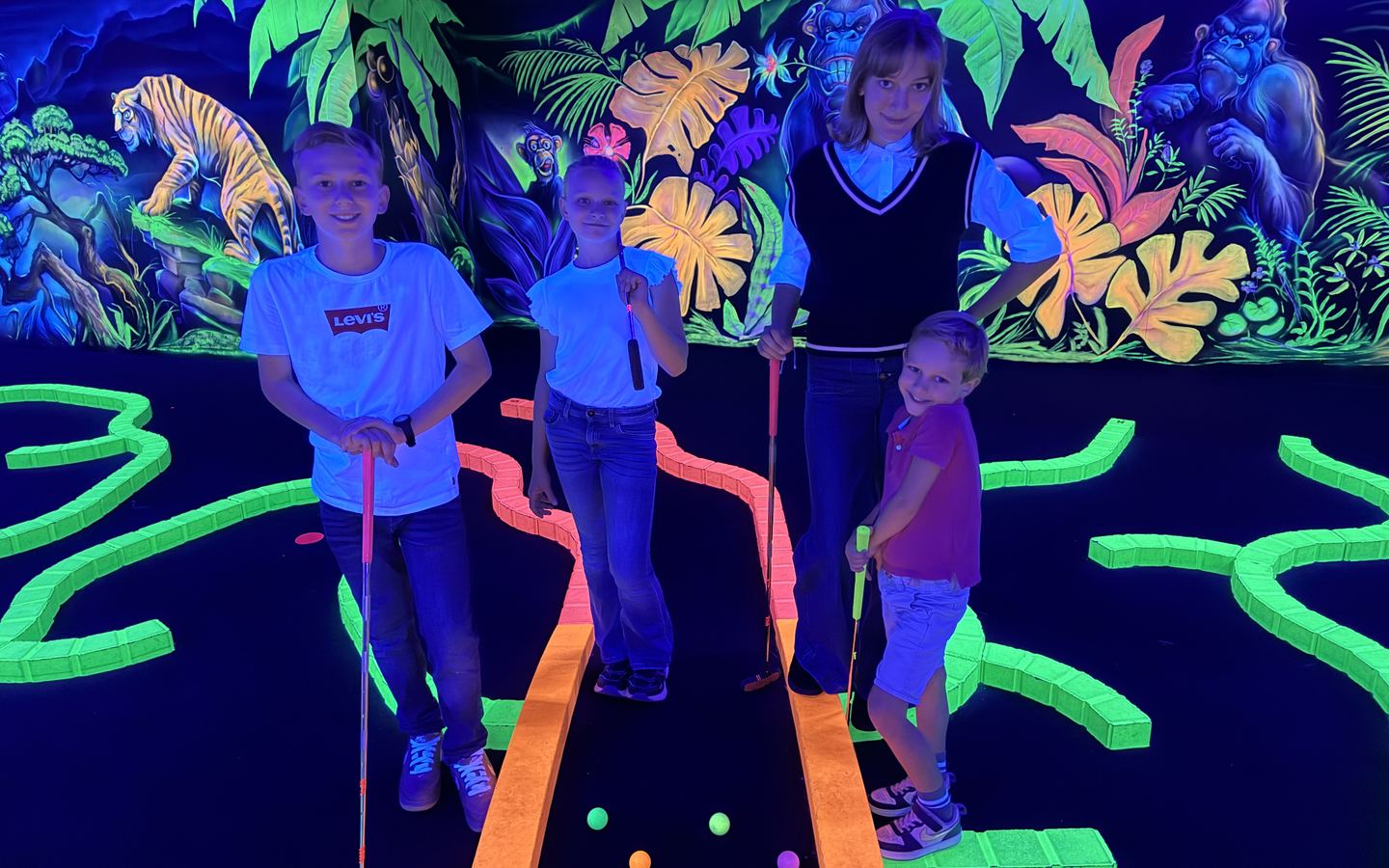 Quatre enfants, club en main, sur le mini-golf fluo Goolfy de Game Parc à Poitiers