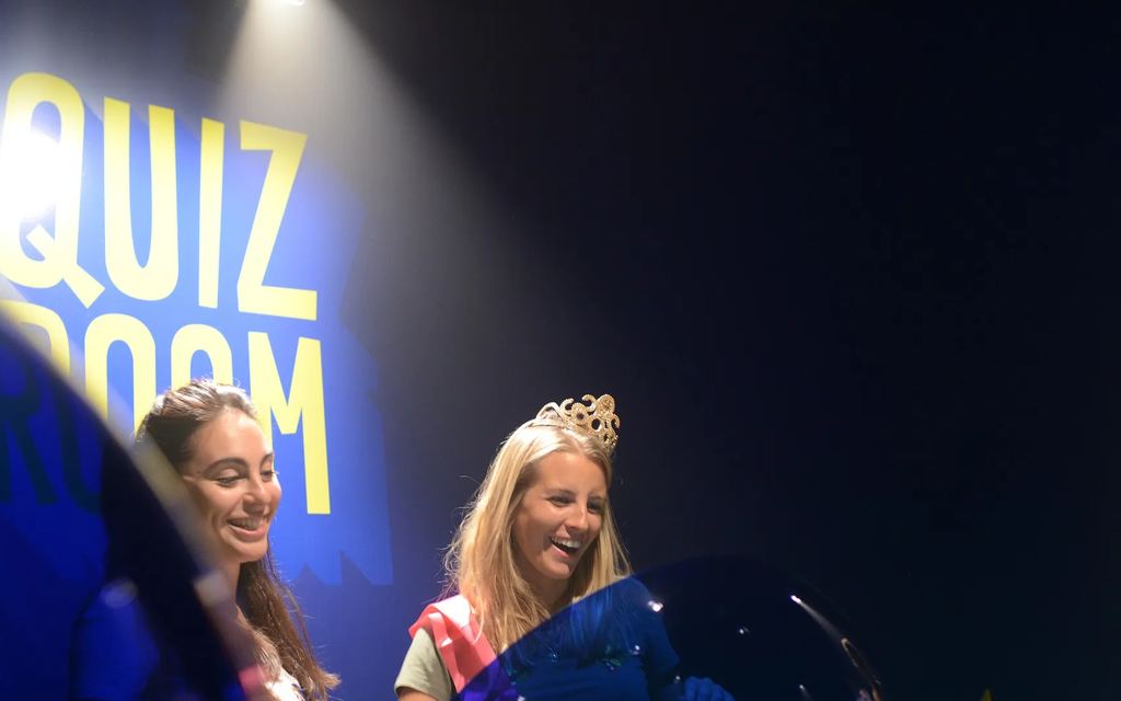 La future mariée, diadème et écharpe, et son amie au pupitre de Quiz Room, pour un EVJF chez Game Parc à Poitiers