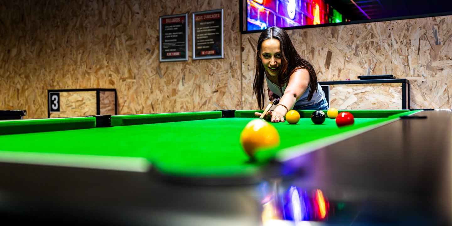 Joueuse qui vise une boule jaune sur une table de billard anglais, Game Parc Poitiers