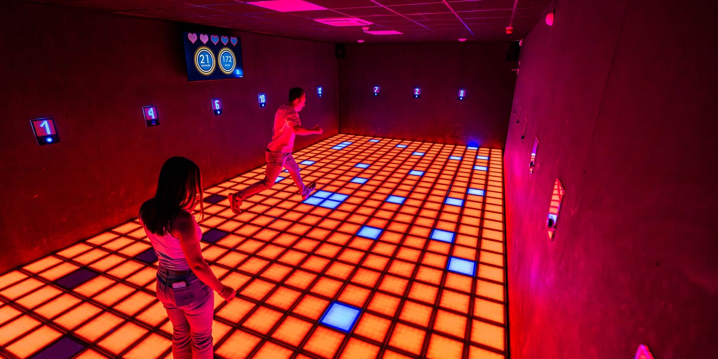 Partie en équipe sur le sol de dalles lumineuses, score affiché au mur, Pulse UP Poitiers
